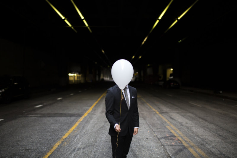 Person with white balloon in front of his head, ensuring his privacy